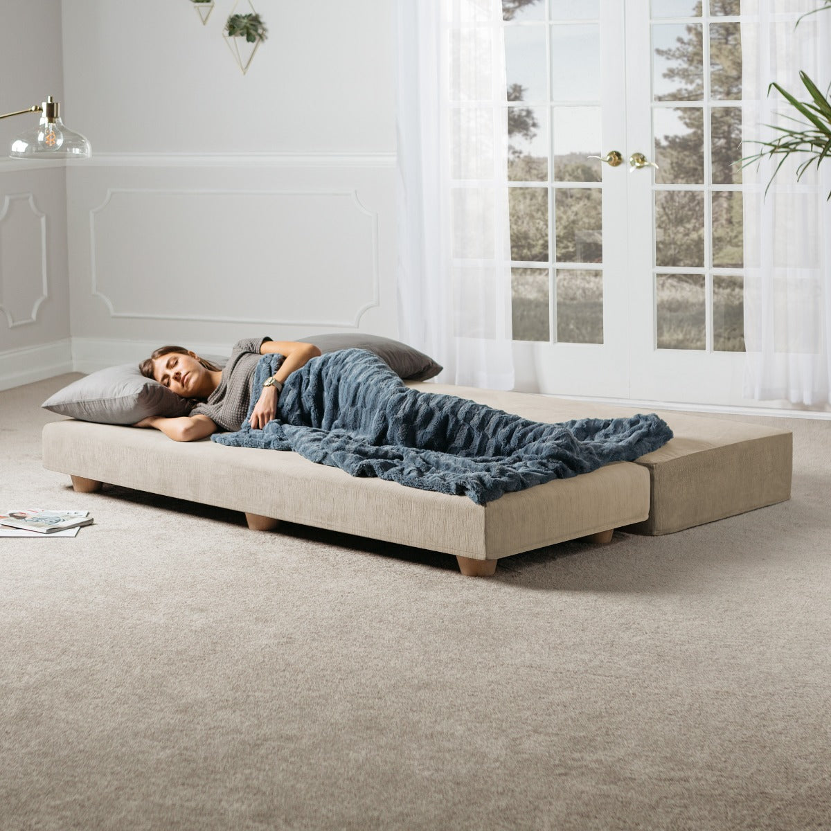 Woman lying on Alon Convertible Daybed with Wood Feet - Microvelvet Ivory