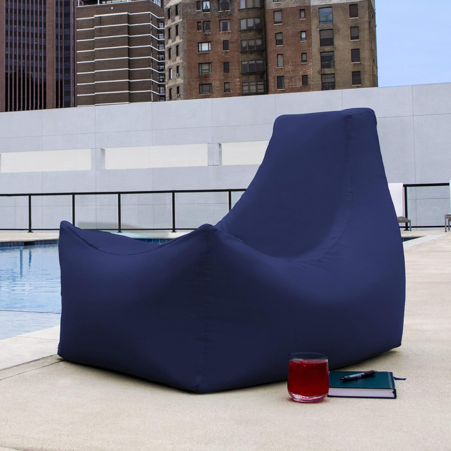 Blue bean bag chair on a rooftop with a pool and cityscape in the background