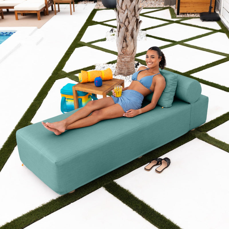 Woman relaxing poolside while lounging on the Alvy Outdoor Daybed Lounger in sunbrella breeze