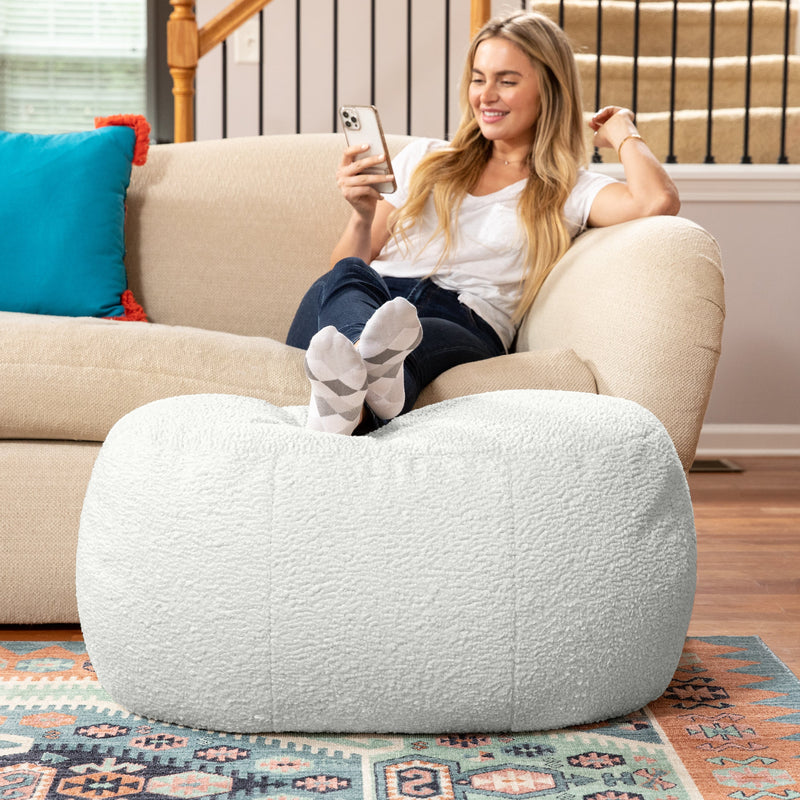Woman sitting on couch resting legs on Ellis Ottoman large in white in living room