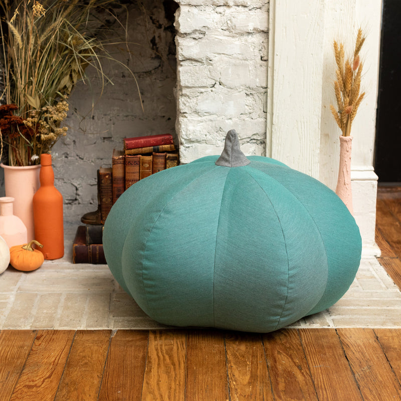 Green Pumpkin Pouf sitting by fireplace