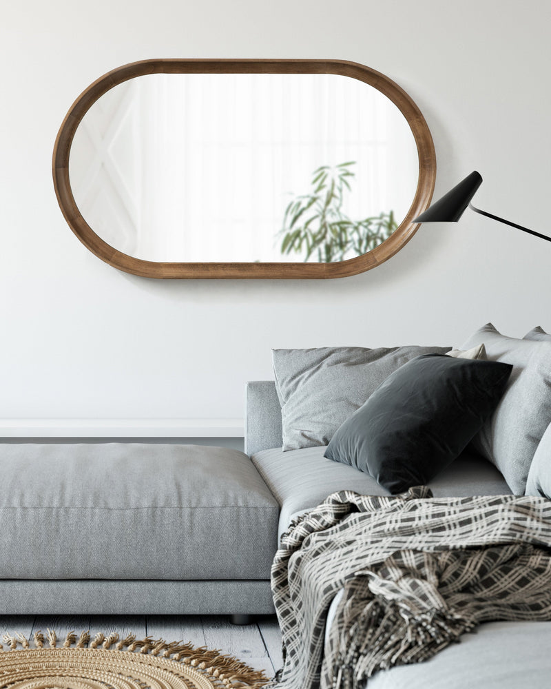 Hatherleigh capsule mirror hung horizontally above a gray sofa