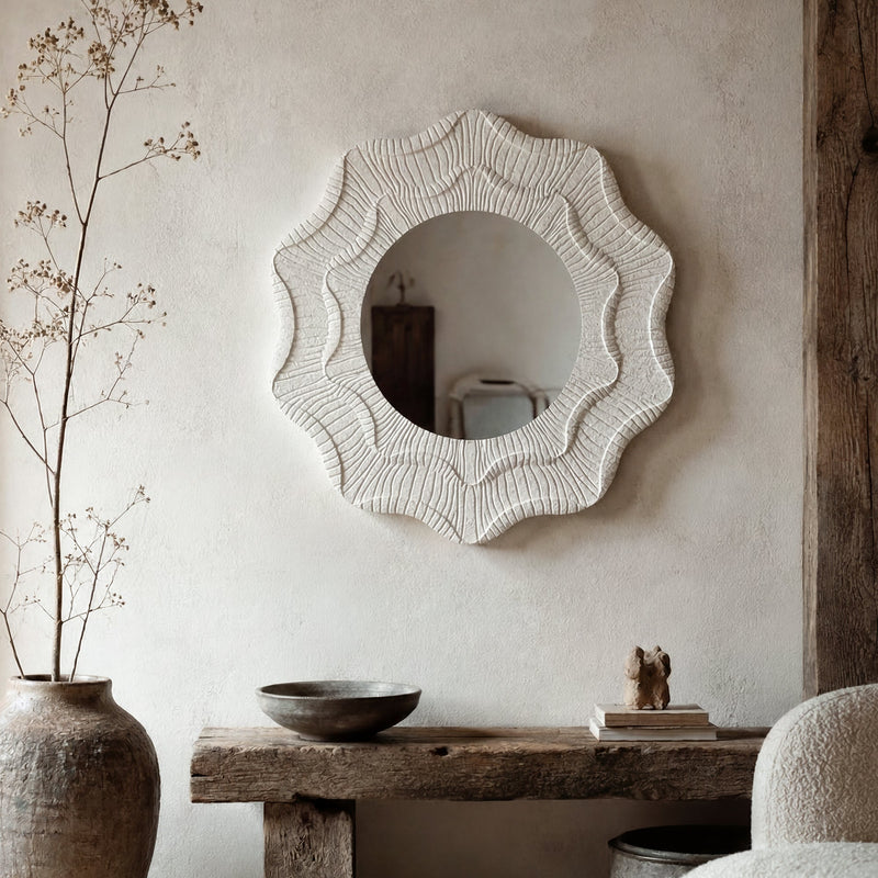 Wavy flower wall mirror hung above a rustic bench with a vase of branches