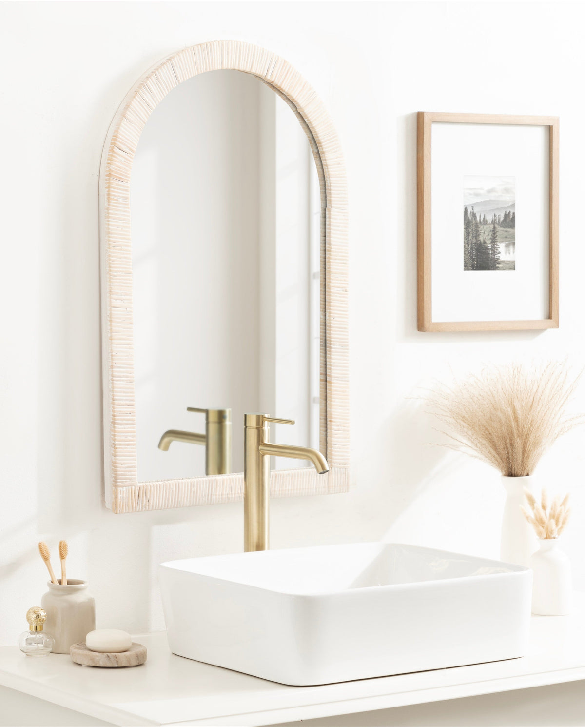 White rattan arch mirror above a vanity