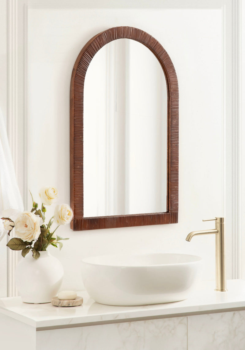 Brown rattan arch mirror above a bathroom sink