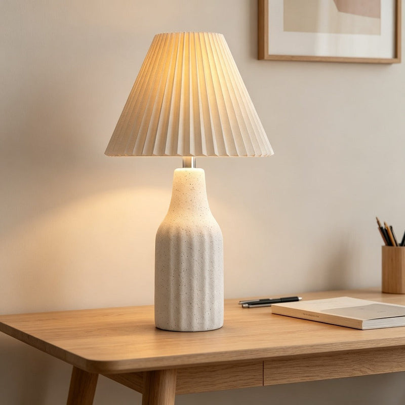 Pleated Shade Ceramic Lamp lit on a wood desk
