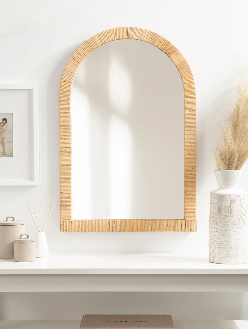 Natural rattan arch mirror above a bathroom sink