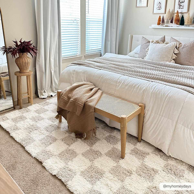 Checkered shag rug under a bed with a wood bench