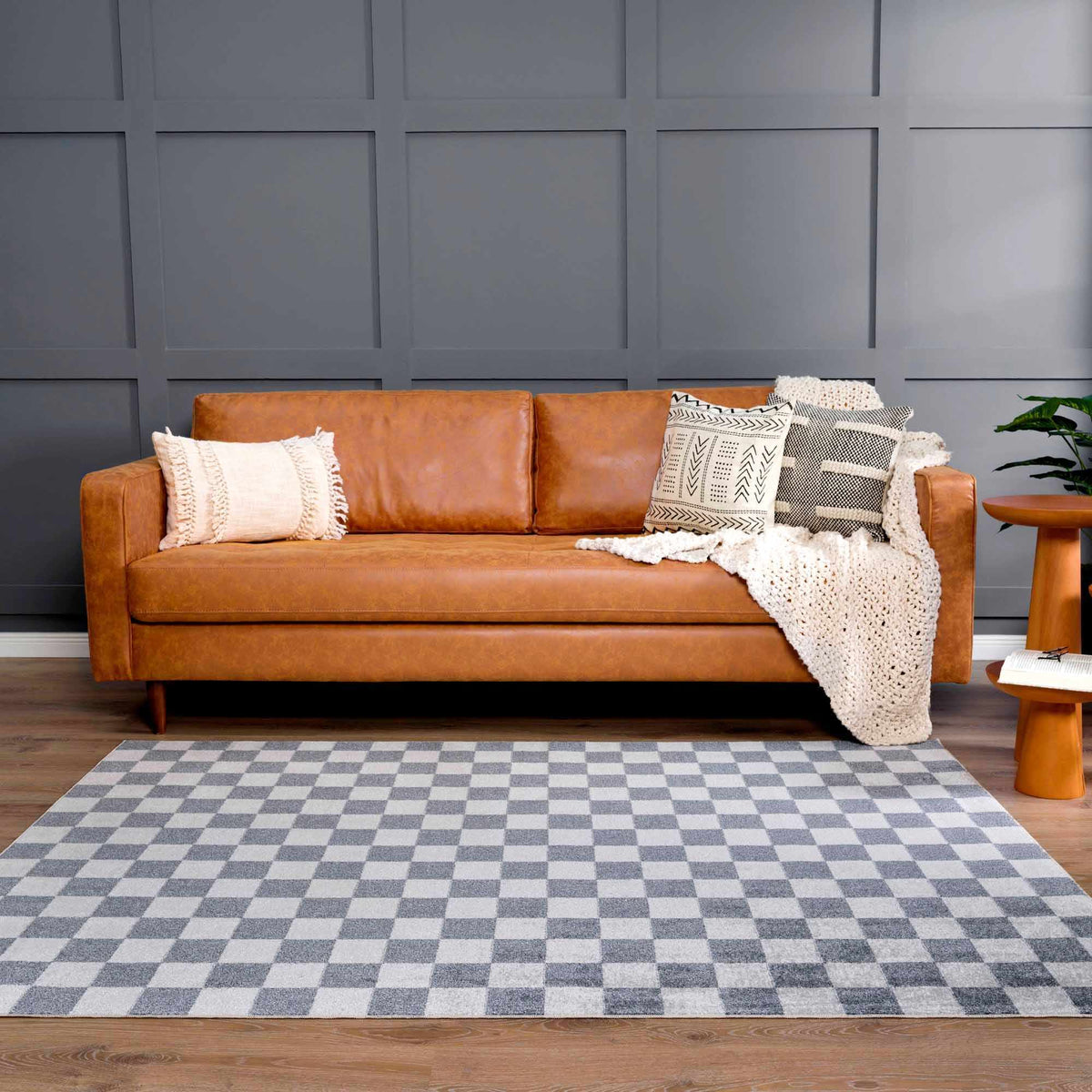 Alie checkered rug under a sofa against a navy wall