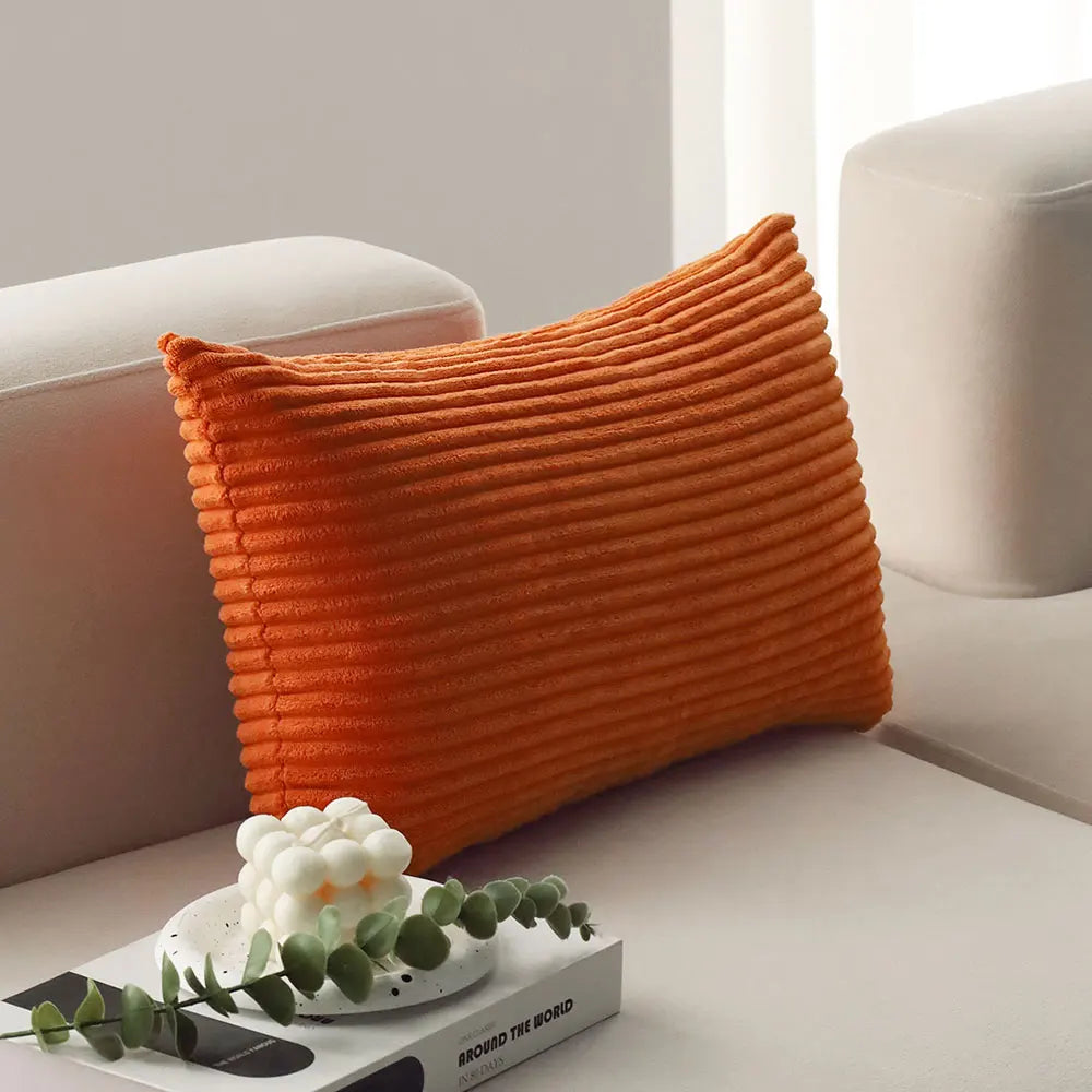 Orange corduroy lumbar pillow on a sofa arm