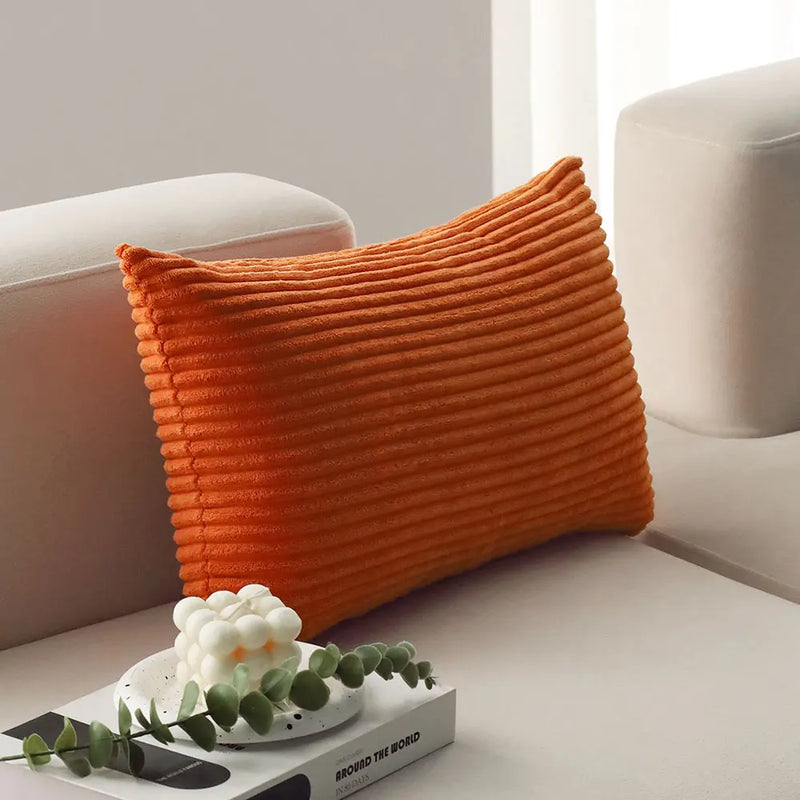Orange corduroy lumbar pillow on a sofa arm