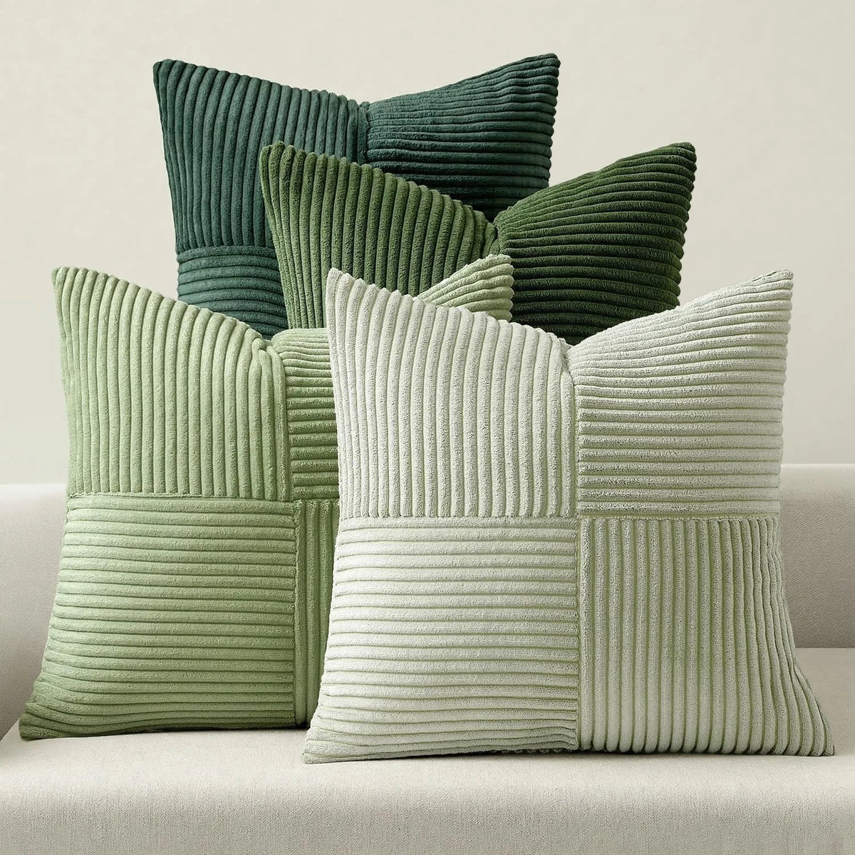 Patchwork corduroy pillow covers in shades of green on a sofa