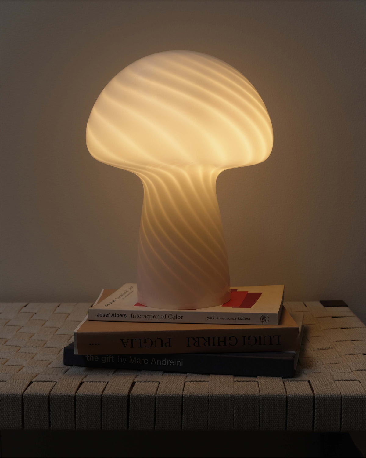 Mushroom Table Lamp lit on a stack of books