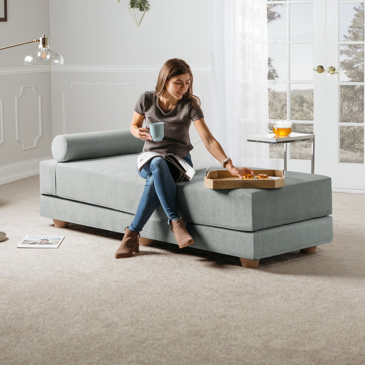 Woman sips a cup of tea on Alon Convertible Daybed with Wood Feet - Microvelvet Ice
