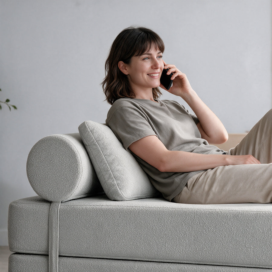 Avida Bolster and Pillow Refresh in Dark Gray Boucle behind a woman relaxing on the Avida Daybed