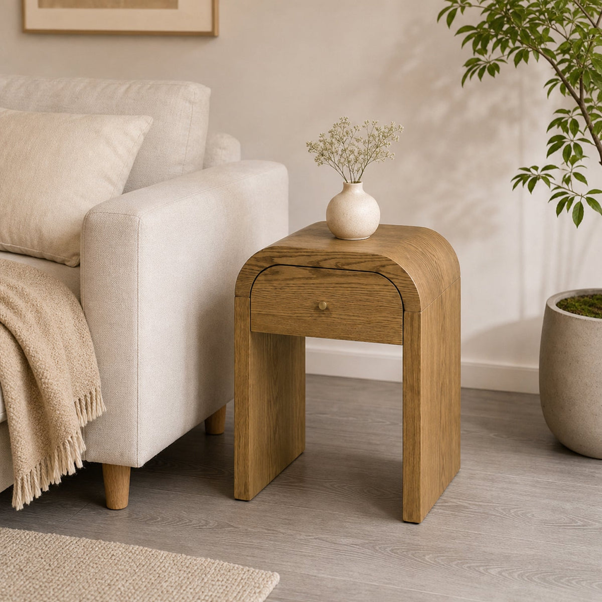 Curved Side Table with Drawer beside a cream armchair