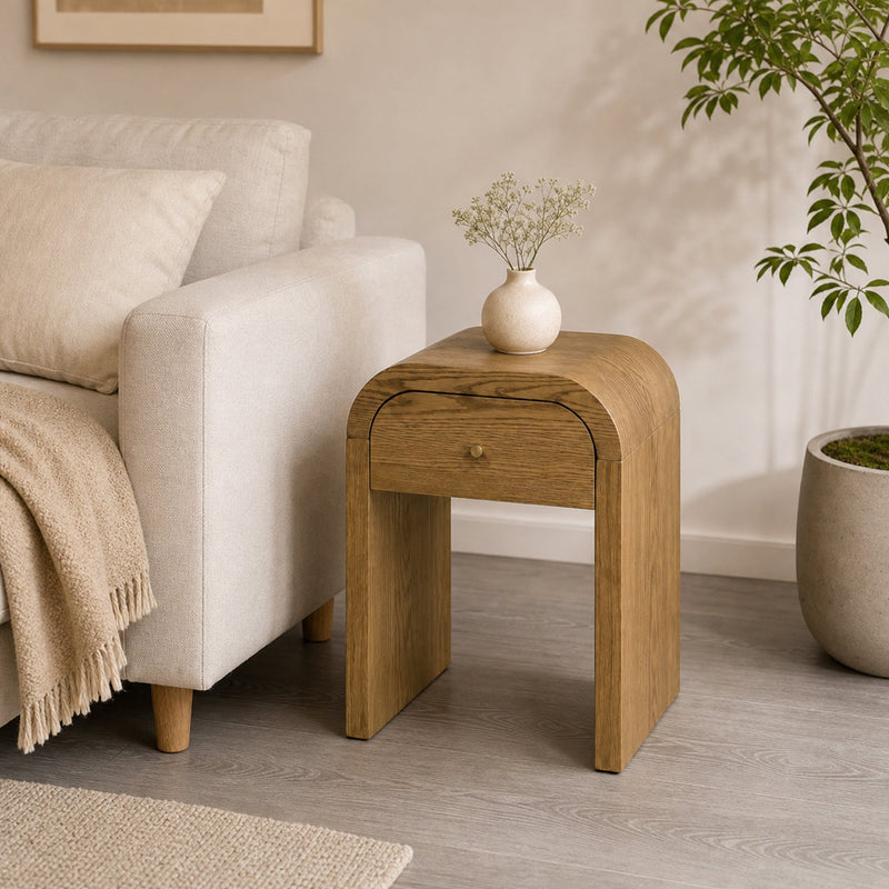 Curved Side Table with Drawer beside a cream armchair