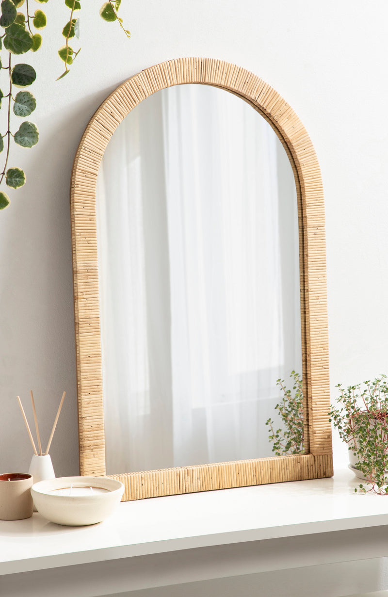 Natural rattan arch mirror above a vanity