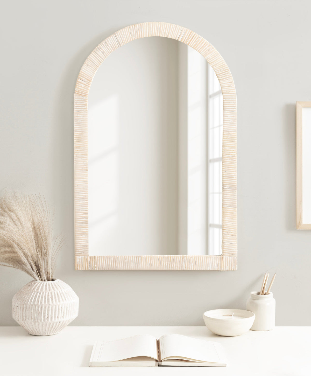 White rattan arch mirror above a bathroom sink