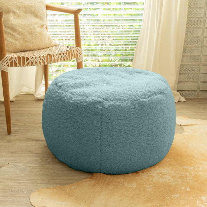 Blue textured ottoman on a wooden floor with a chair and window in the background
