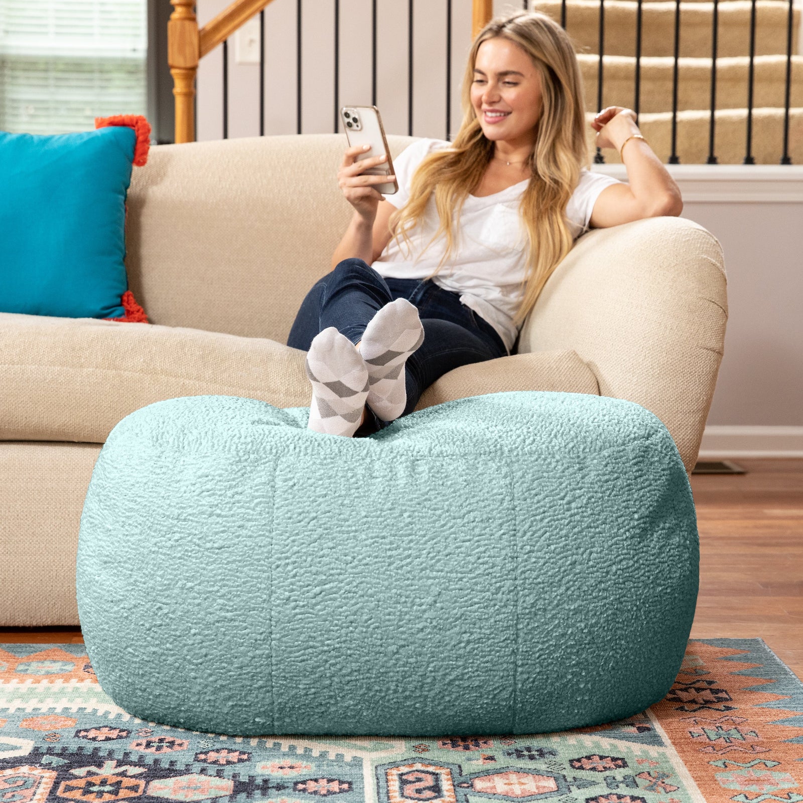 Woman resting legs on Ellis Ottoman large in mineral green in living room