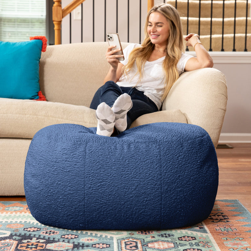 Woman sitting on couch resting legs on Ellis Ottoman large in blue in living room