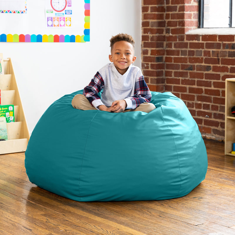 Child sitting on a teal bean bag chair in a room with a brick wall and colorful decorations.
