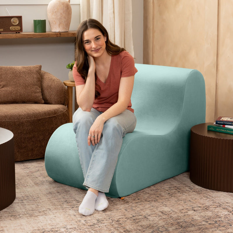 Woman sitting and smiling while on the Uptown West Chair - Empire III Caribbean