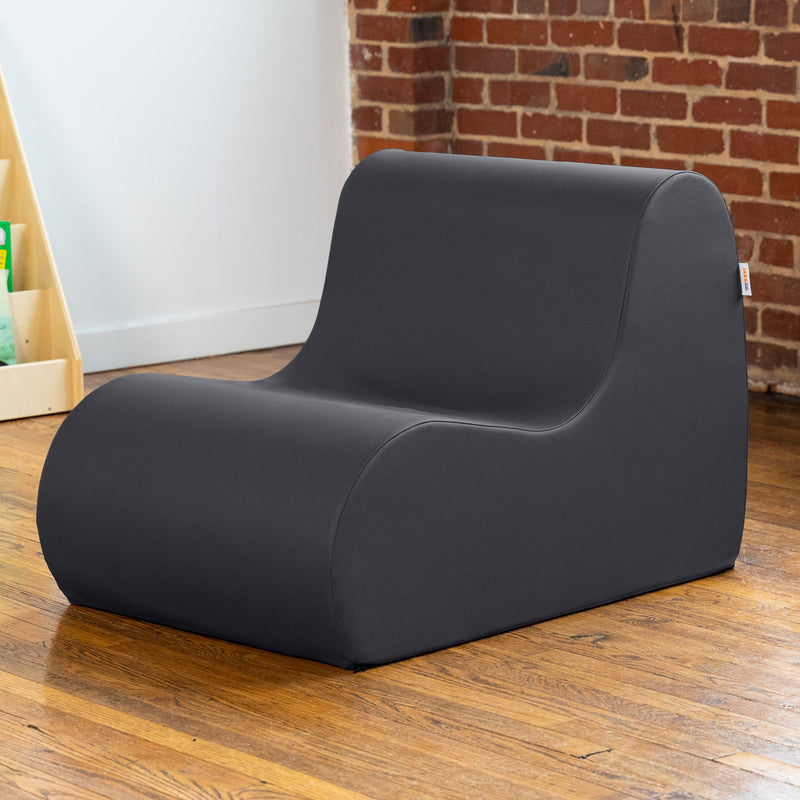 Modern black chair on a wooden floor with a brick wall in the background