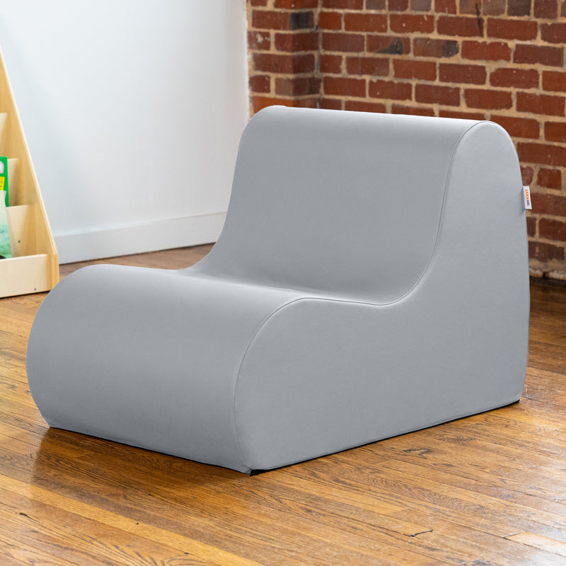 Gray children's chair on a wooden floor with a brick wall in the background
