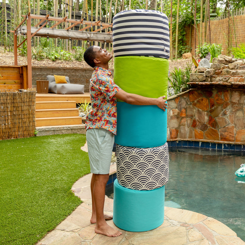 Person interacting with a colorful cylindrical seat in a backyard setting